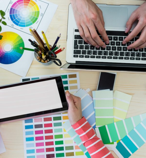 Hands of graphic designers using laptop and digital tablet in office